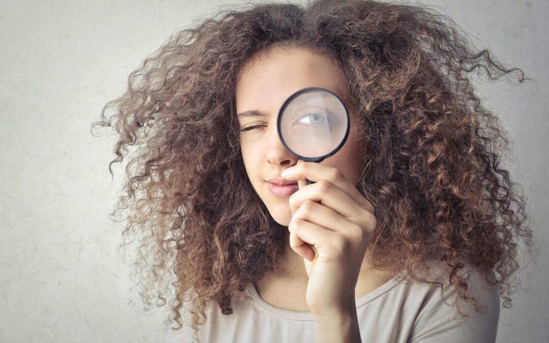 Person looking through magnifying glass